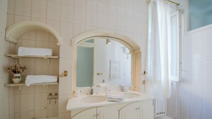 Ein Badezimmer mit zwei Waschbecken, einer Badewanne, einem Spiegel und einer Duschvorhang.