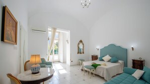 Ein Schlafzimmer mit einem Bett, einem Schlafsofa, einem Tisch mit Lampe und einem Sessel.