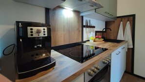 A modern kitchen with a black coffee maker, a wooden countertop, and a built-in oven. - Great Apartment Near the ski Area (Schwendau)