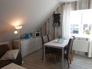 Enjoy meals in this inviting dining area with a table for four, a lamp, and a sofa and armchair for comfortable seating.