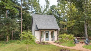 A small house with a sloped roof, surrounded by a well-maintained lawn and trees. - The  Willow  Cottage (TYLER)