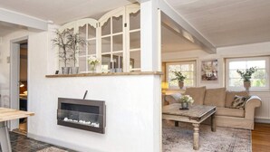 A cozy living room with a fireplace, a sofa, a coffee table, and a rug. - 4 Person Holiday Home in Skaerbaek (Skaerbaek)