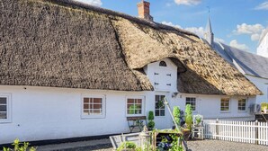 A traditional thatched-roof house with a white exterior, a small porch, and a gravel driveway. - 4 Person Holiday Home in Skaerbaek (Skaerbaek)
