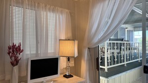 Et hotelværelse med et Samsung-TV, en lampe og udsigt til balkonen.