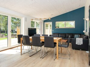 A modern living room with a dining area, large windows, and a view of the outdoors. - 4 Star Holiday Home in Oksbol (Oksbol)