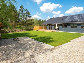 A modern house with a covered patio, solar panels, and a well-maintained lawn. - 4 Star Holiday Home in Oksbol (Oksbol)