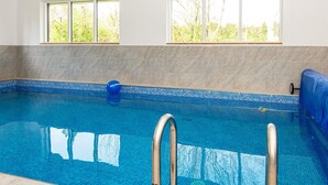 Ein Hallenbad mit klarem, blauem Wasser, einem blauen Ball und einer Leiter.