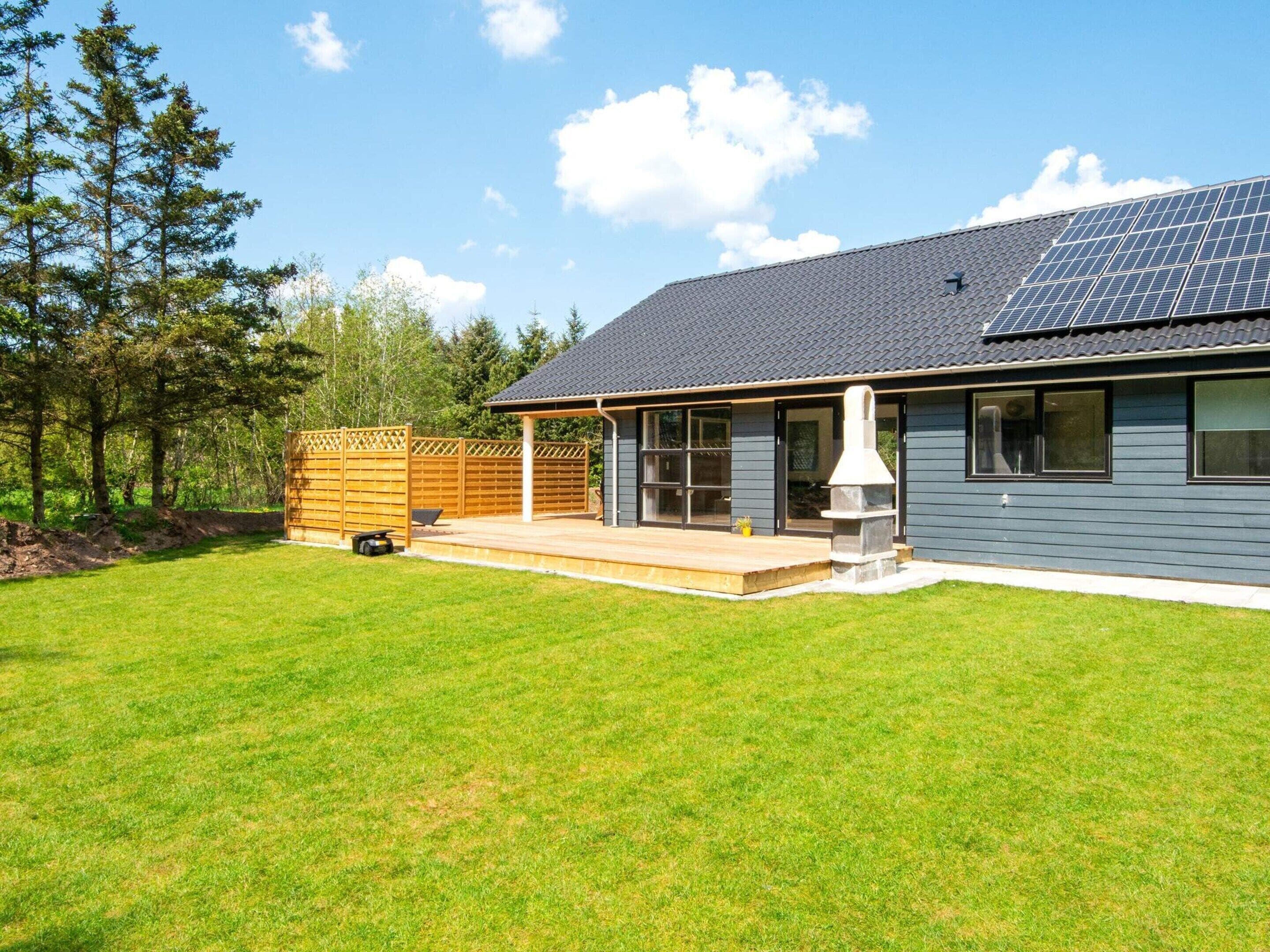 A residential building with a covered patio, solar panels, and a fenced backyard.