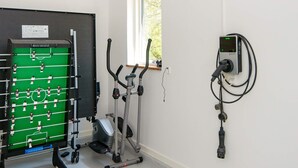 Ein Zimmer mit Kicker, Fitnessgeräten und einem wandmontierten Gerät.