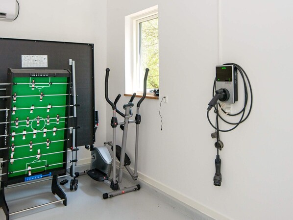A room with a foosball table, exercise equipment, and a wall-mounted device.