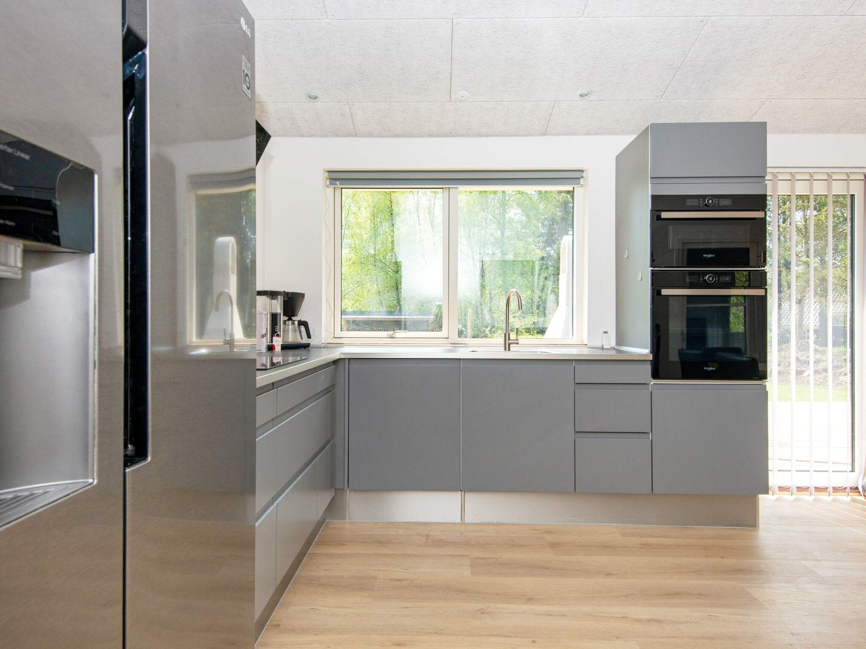 Una cocina moderna con un ventanal grande, electrodomésticos integrados y piso de madera.