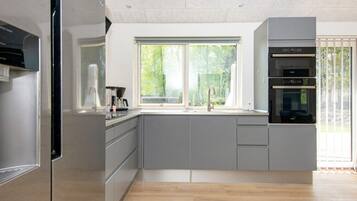 Una cocina moderna con un ventanal grande, electrodomésticos integrados y piso de madera.