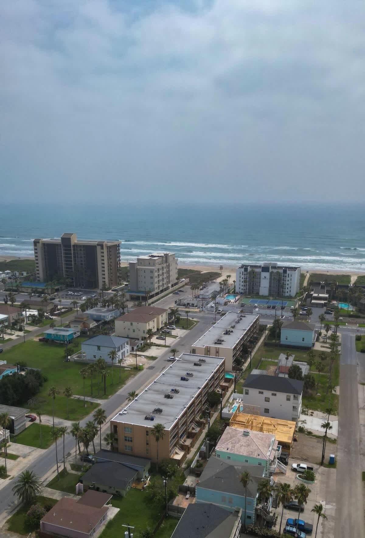 An aerial view of a coastal urban area with buildings, roads, and a beach.