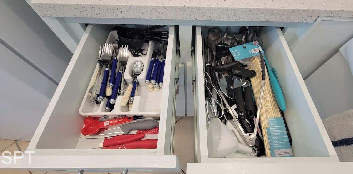 A kitchen drawer with utensils and cookware organized in compartments.