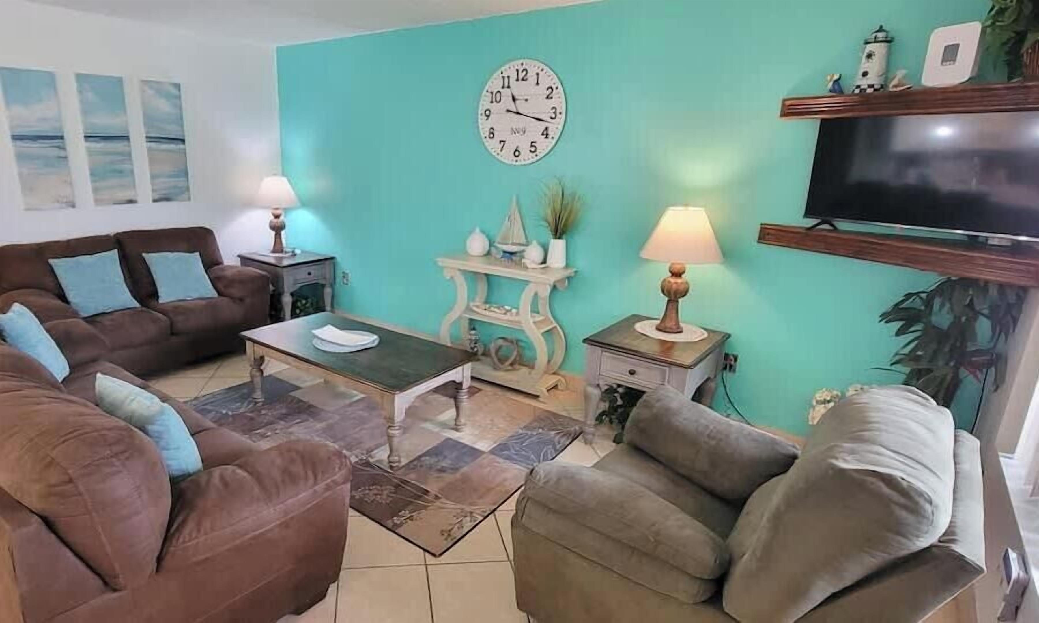 A living room with a brown sofa, a coffee table, and a teal wall.