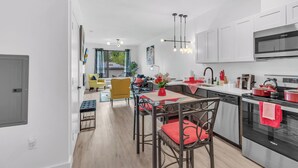 Une cuisine moderne avec des meubles blancs, un four en acier inoxydable et un coin repas comprenant une table et des chaises.