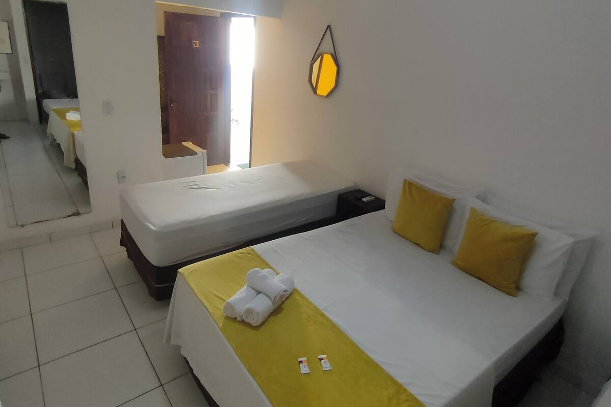 Ein Hotelzimmer mit zwei Einzelbetten, einem großen Bett, einem Spiegel und einer Wandleuchte.