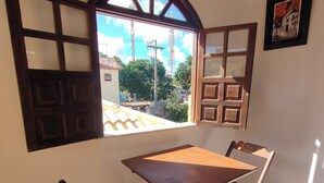 A room with a wooden table and chairs, a window with a view of buildings, and a 'No Smoking' sign. - Pousada Caminho das Estrelas (Mata de São João)