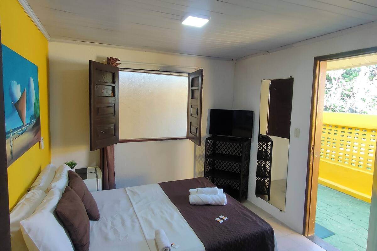 Ein Schlafzimmer mit Bett, Fernseher, Kleiderschrank und Fenster.