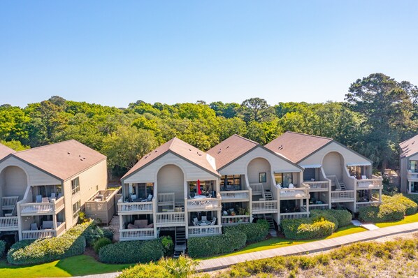 A row of white, two-story cottages with balconies, surrounded by greenery and trees. - Oceanfront direct beach access, Pools, Golf, Amenity Card - 1370 Pelican Watch (Seabrook Island)