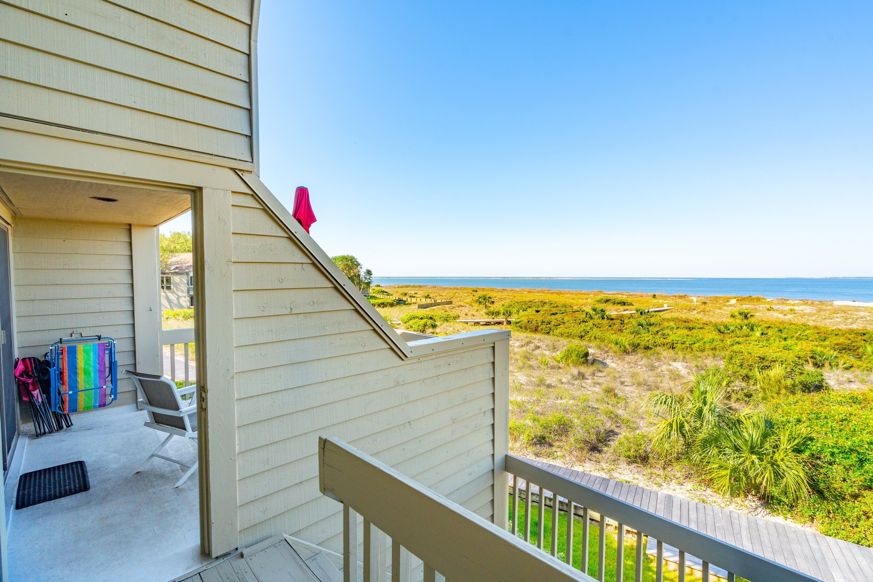 A balcony with a view of the beach and ocean.