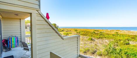 A balcony with a view of the beach and ocean.