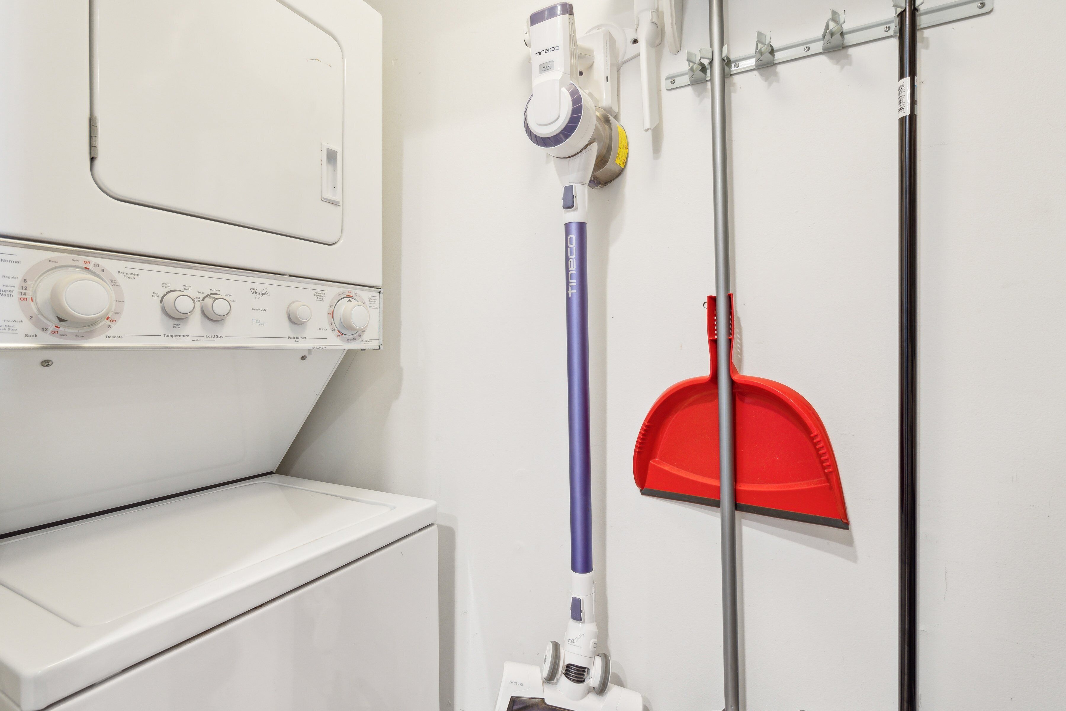 A laundry area with a washing machine, a mopping machine, and a red dustpan on a wall.