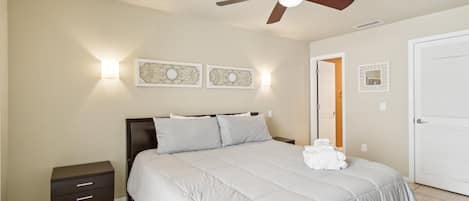 A bedroom with a bed, a nightstand, a ceiling fan, and wall-mounted light fixtures.