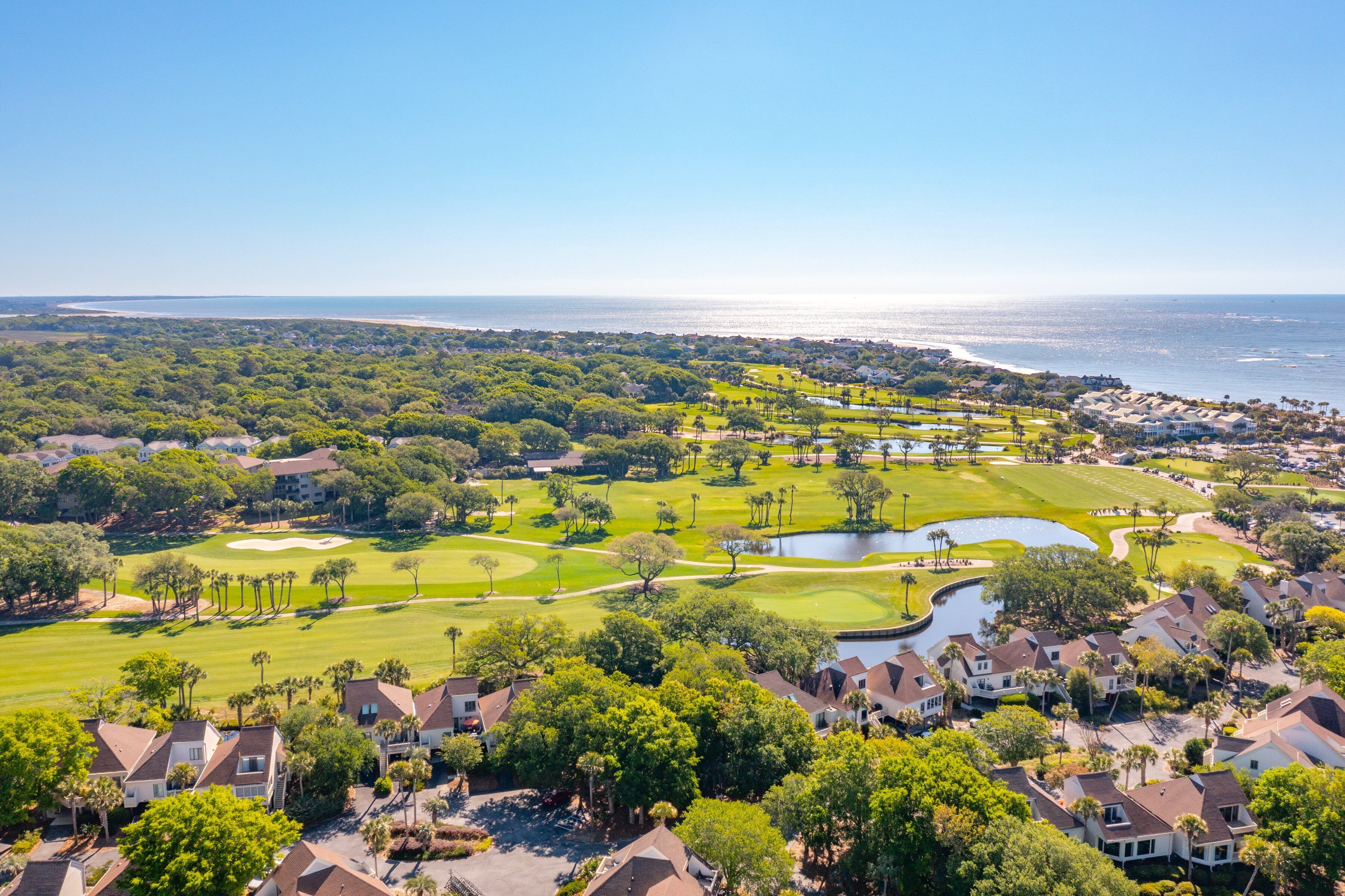 A golf course with a water hazard, surrounded by residential housing and a beach.