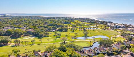 A golf course with a water hazard, surrounded by residential housing and a beach.