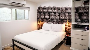 Une chambre à coucher avec un lit, un mur recouvert de boîtes de rangement et une fenêtre.
