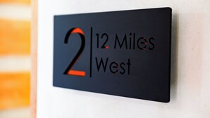 Un panneau noir avec une inscription blanche indiquant « 12 miles à l’ouest ».