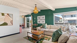 Uma sala de estar espaçosa, com uma parede de destaque verde, teto branco e uma janela grande.