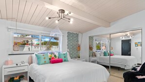 Quarto com uma cama grande, mesa de cabeceira, cadeira, espelho e janela com vista para o exterior.