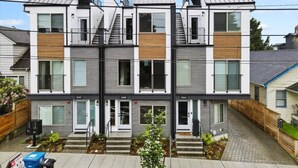 A modern multi-story residential building with a symmetrical facade, multiple balconies, and a central staircase. - 3BR 2.5BA Rooftop View Green Lake Hideaway near UW (Seattle)