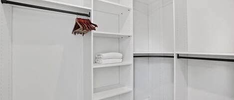 Een witte kast met open planken en een kledingroede.
