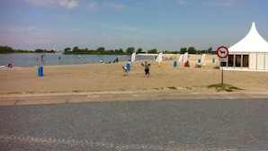 A beach with a white tent, windsurfing equipment, and a no dogs sign. - Beachvilla Grachtenblik (Makkum)