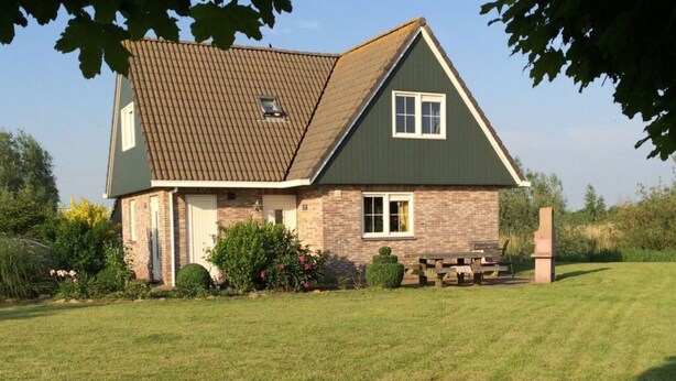 A two-story house with a brick facade and a green roof. - Beachvilla Grachtenblik (Makkum)