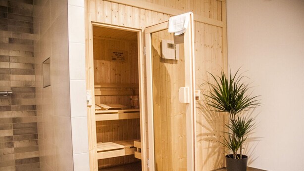 A wooden sauna with a tiled floor and a potted plant beside it. - Small House Lake Modern Retreat (Feldberger Seenlandschaft)
