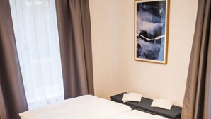 A modern hotel room with a large bed, a bedside table, a wall-mounted artwork, and a window with curtains. - Small House Lake Modern Retreat (Feldberger Seenlandschaft)