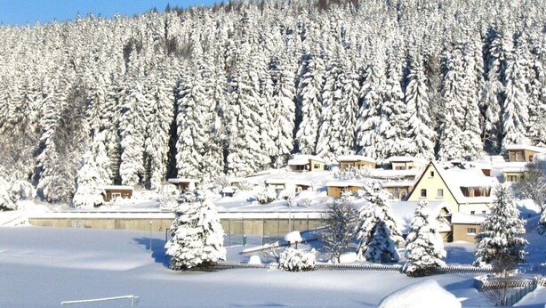 A snow-covered landscape with a row of houses and a large building in the background. - Daumler "house Am Weisswald" (Breitenbrunn/Erzgeb.)