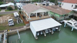 A waterfront property with a covered dock, a house with a balcony, and a boat docked nearby.