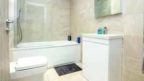 Ein modernes Badezimmer mit einer gläsernen Duschkabine, einer weißen Badewanne und einer Toilette.
