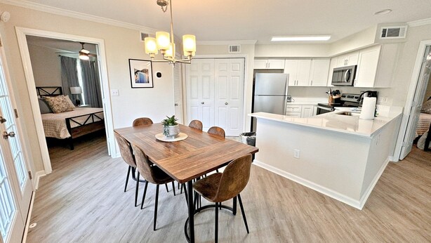 A modern kitchen with white cabinets, a stainless steel refrigerator, and a microwave.