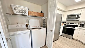 A compact kitchen with a washing machine, dryer, microwave, and oven.