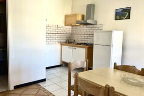 A compact kitchen with a stove, refrigerator, and wooden cabinets.