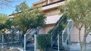 Un edificio con facciata rosa, scale in metallo e vegetazione circostante.