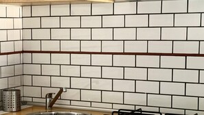 Una cucina con piastrelle bianche a metrò, un lavello in acciaio inossidabile, un fornello a gas e mobili in legno.