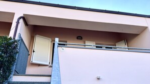 Un edificio con facciata beige, ringhiera in metallo e porta con persiana chiusa.