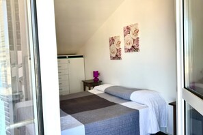 A bedroom with a bed, a nightstand, a lamp, and a window.